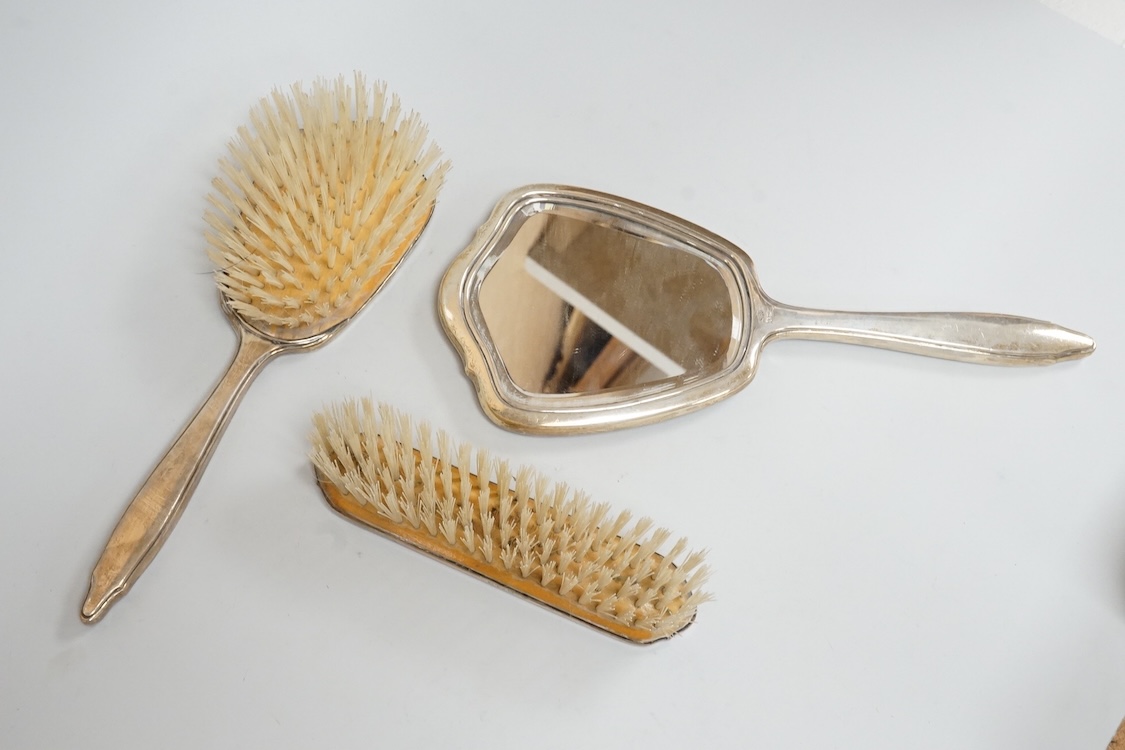 An early 1960's silver mounted hand mirror, 24.7cm and two matching brushes, Adie Bros. Birmingham, 1960.